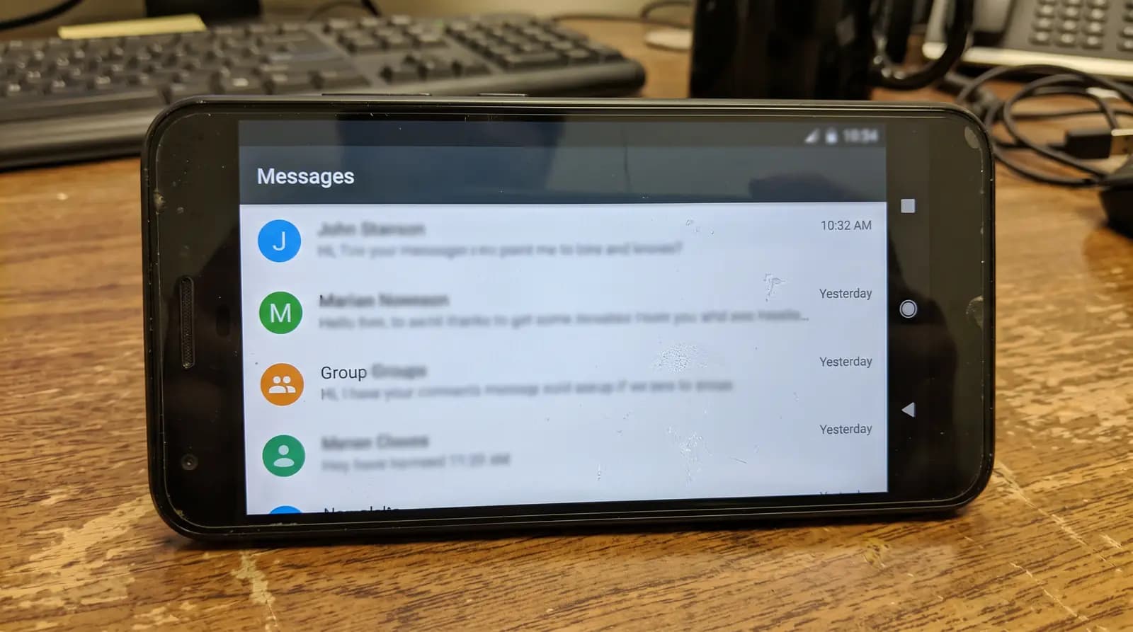 Celular sobre a mesa mostrando uma lista de conversas